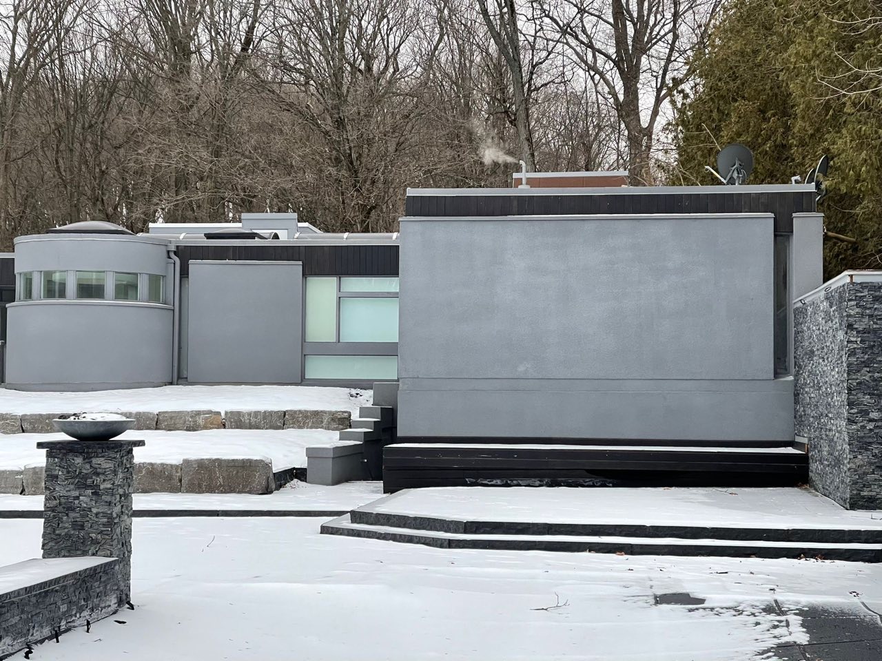 Finished grey contemporary residence with landscaped stonework in winter